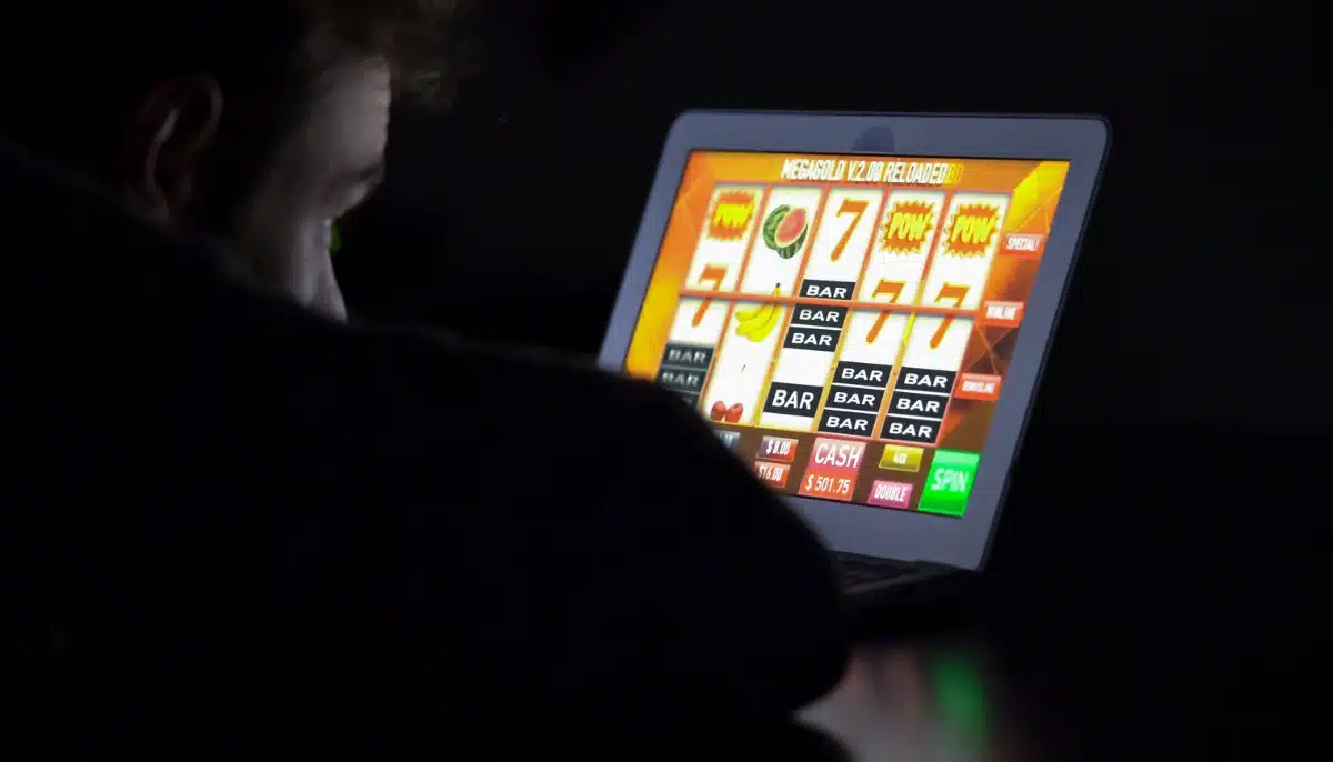 Person spelar på en digital spelautomat i en mörk miljö