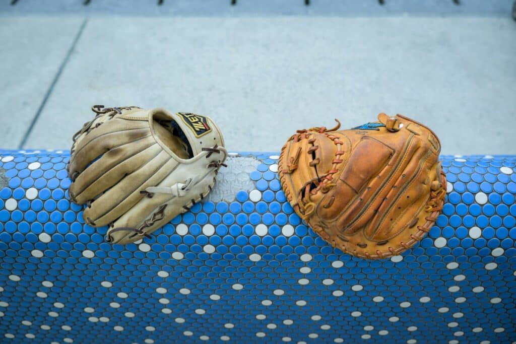 A pair of baseball gloves resting on a blue and white rail