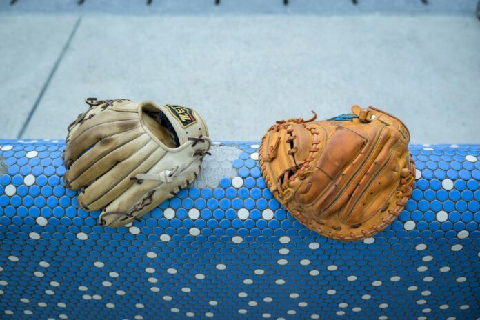 A pair of baseball gloves resting on a blue and white rail