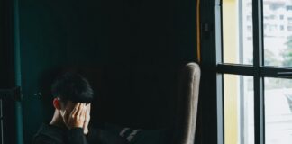 a person sitting in an office with their hands over their face