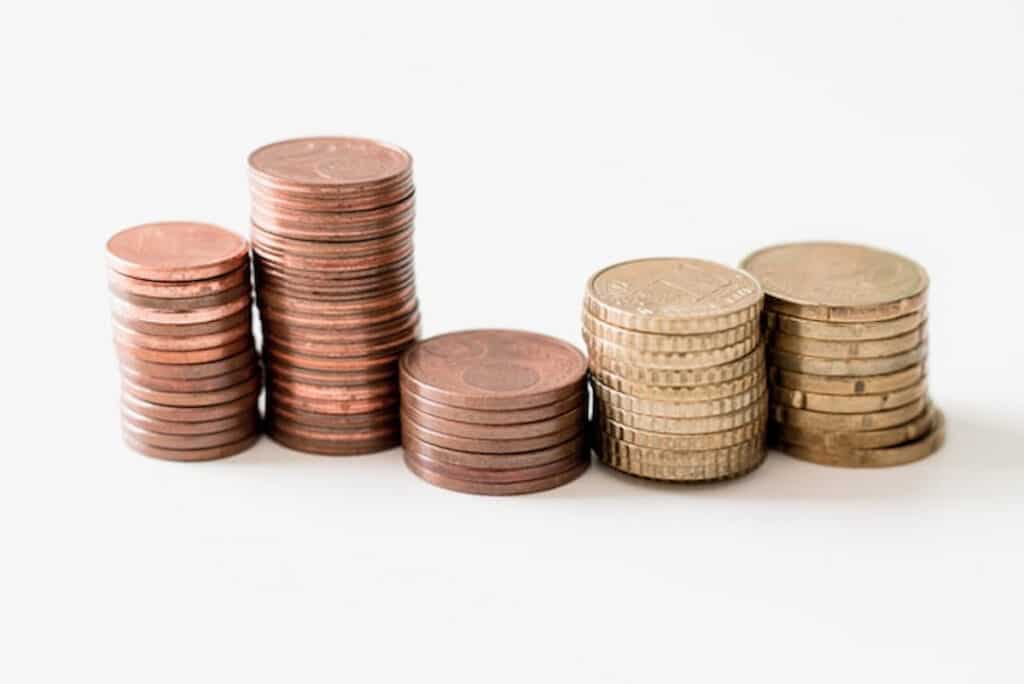 Stacks of copper and gold coins arranged in ascending order on a white background.