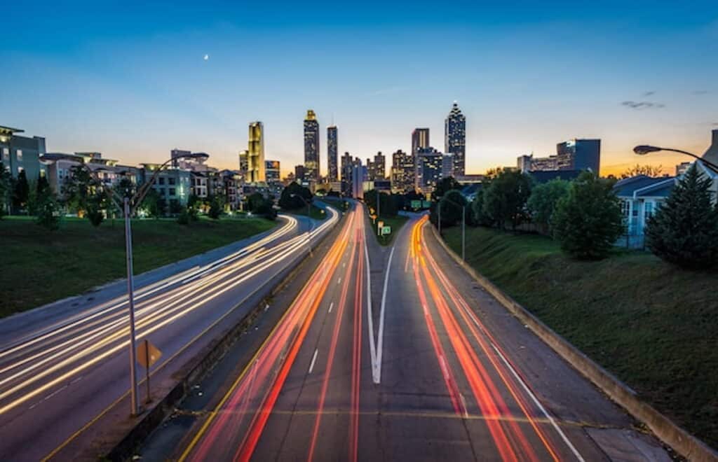 Atlanta skyline at dusk with light trails from highway traffic in the foreground.