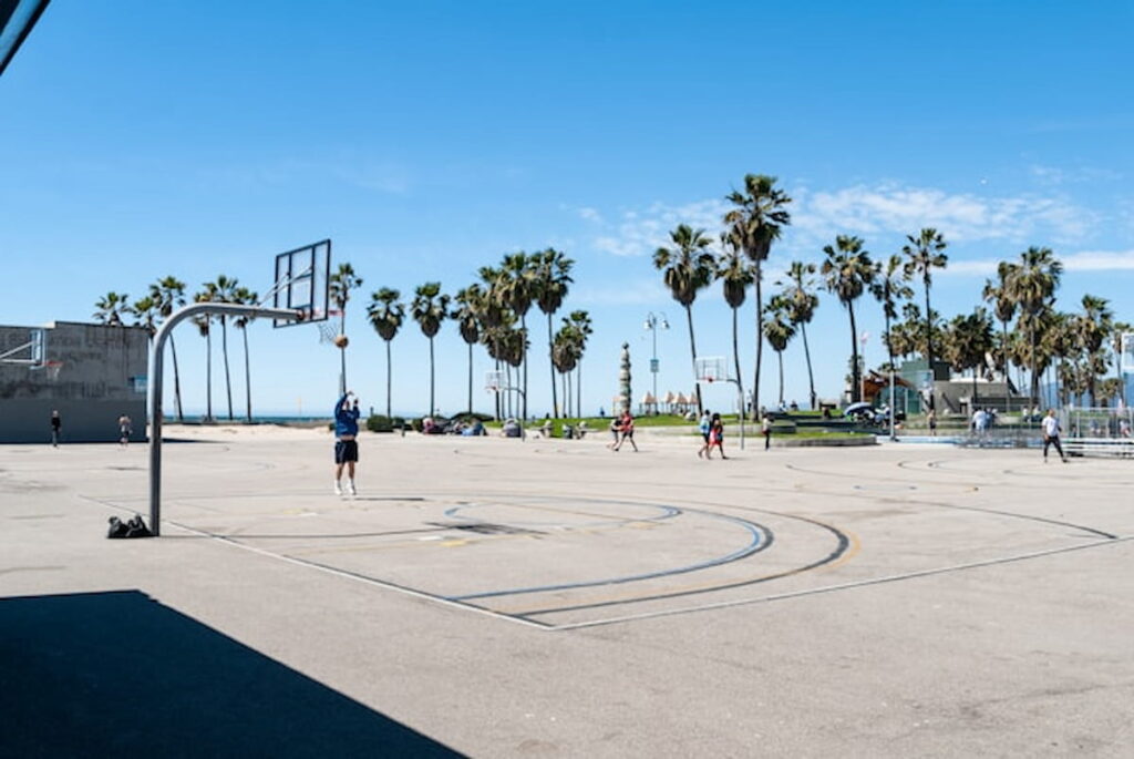 Outdoor basketball court with palm trees and players at Venice Beach, California