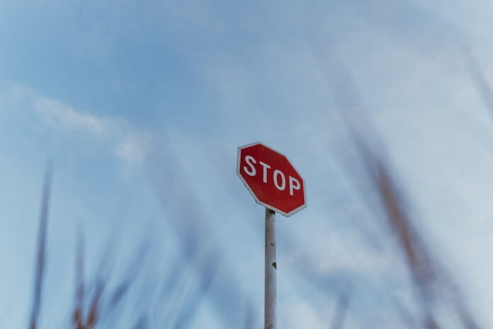 Stop sign against a blue sky, symbolizing legal enforcement and regulatory warnings.