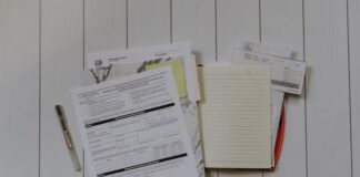 Republican Lawmaker Introduces Third Bill to Reverse Gambling Loss Deduction Cap A stack of tax documents, envelopes, and a notepad lay out on a white wooden table, alongside a pen.