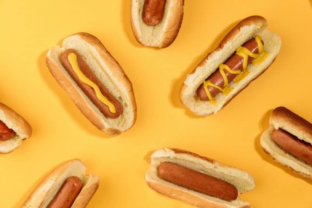 A series of hot dogs displayed on a yellow background