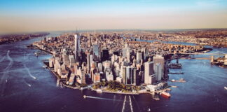 Aerial view of Lower Manhattan skyline at sunset with surrounding rivers and bridges.