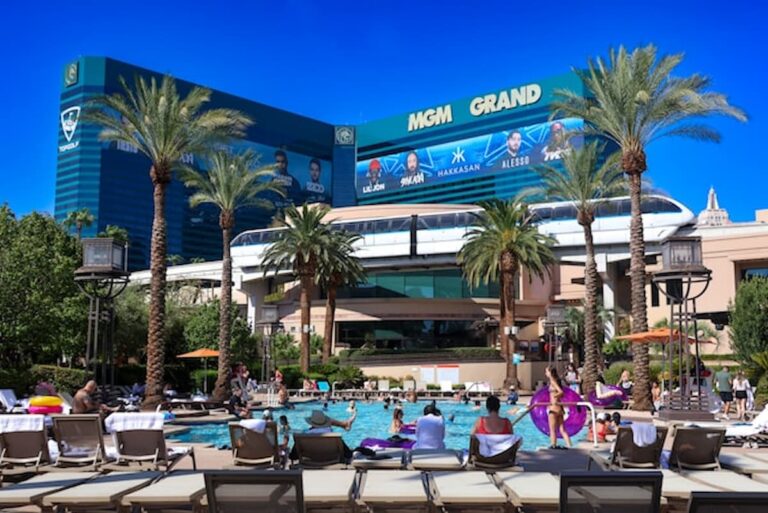 Guests relax at the MGM Grand Las Vegas pool with the hotel and monorail in the background on a sunny day.