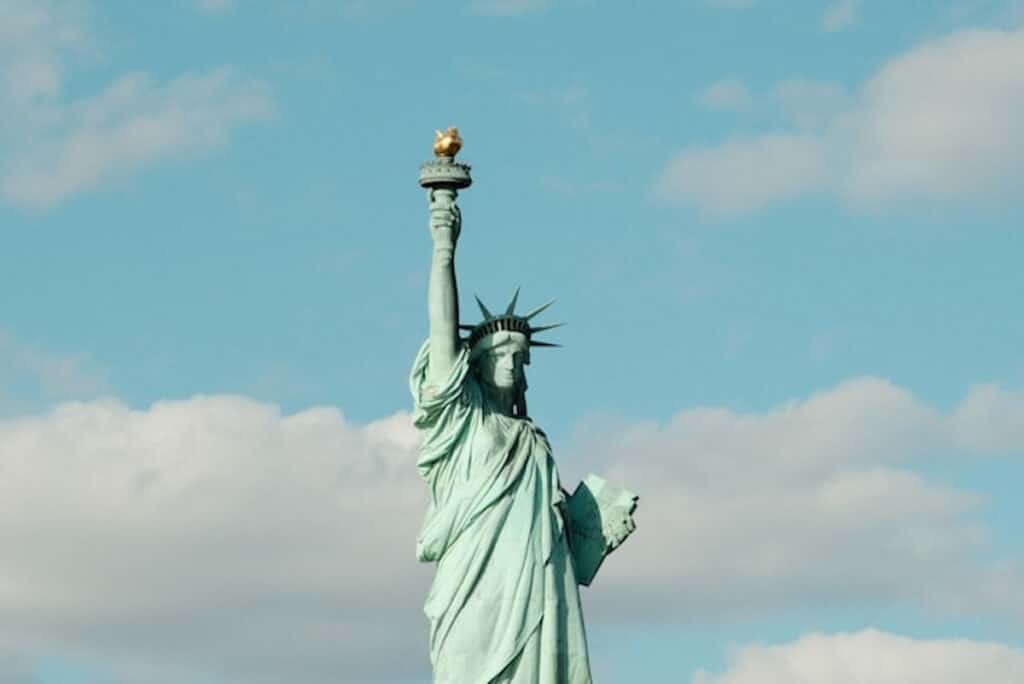 Statue of Liberty against a blue sky with clouds.