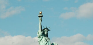 Statue of Liberty against a blue sky with clouds.