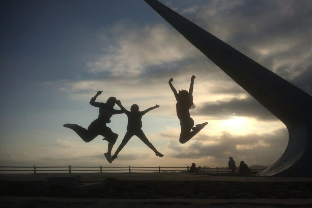 a trio of shadows jumping in the air in a park