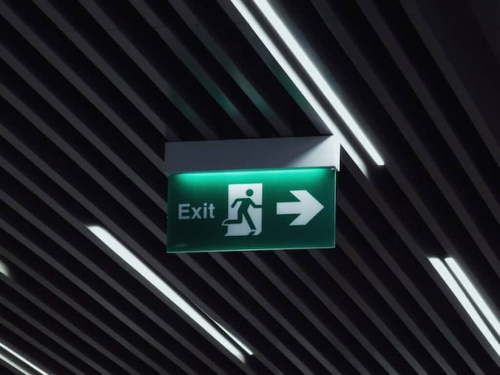 Green exit sign with a running figure and arrow, symbolizing departure or exit.