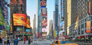 Times Square streetscape with yellow taxi and digital billboards near 1515 Broadway.