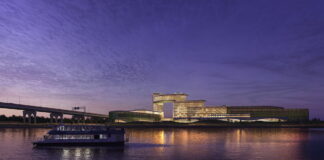 Nighttime rendering of Bally’s proposed Bronx casino resort viewed from the East River with ferry in foreground.