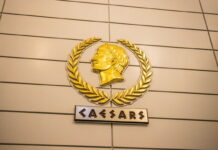 Caesars Q4 Earnings: Digital Sector Thrives, but Company Suffers Large Losses Golden Caesars logo on a wall inside a casino