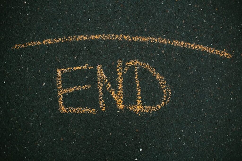 The word “END” written in yellow chalk on asphalt
