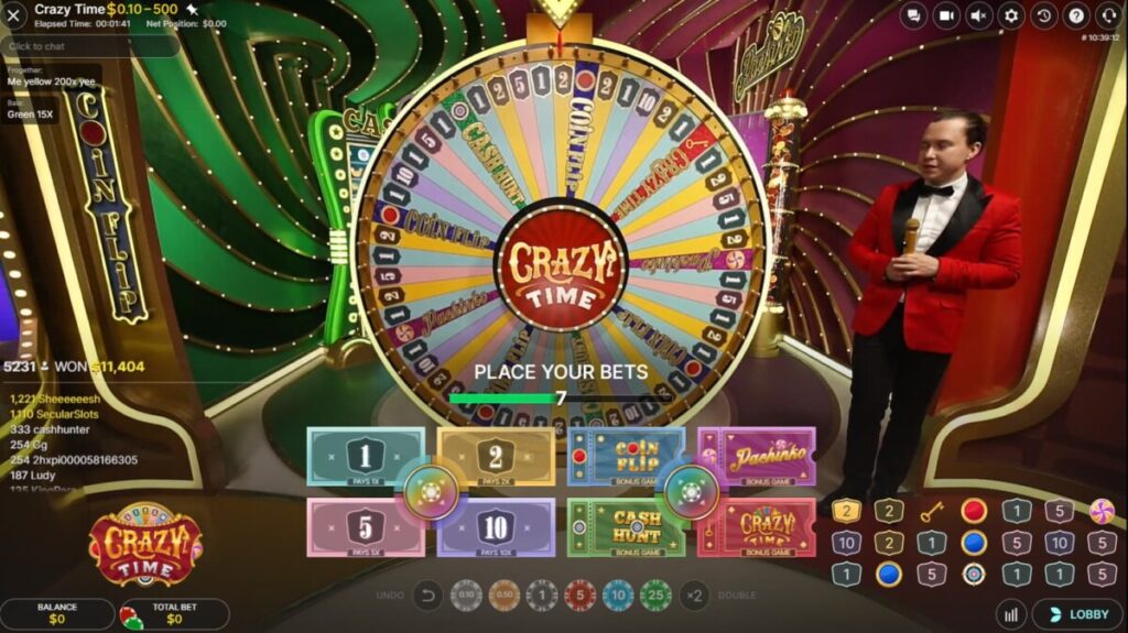 A game show host in a red suit stands beside a large, colorful spinning wheel labeled "Crazy Time," set against a vibrant, illuminated backdrop