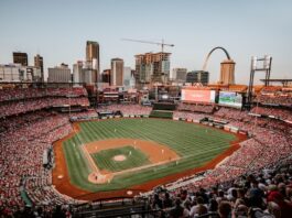 MLB Reportedly Warned Players About Prediction Markets in August Memo Full baseball stadium with downtown St. Louis skyline and Gateway Arch in the background.
