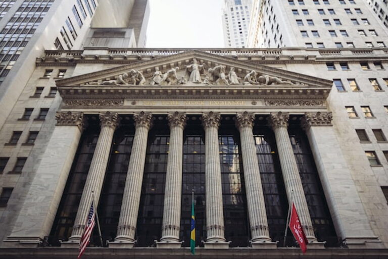 Facade of the New York Stock Exchange with flags and columns.