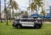 Florida Seizes Over $350K, 623 Slot Machines Amid Lawmakers’ Push for Anti-Gambling Bill Police SUVs parked on grass in front of palm trees and art deco buildings