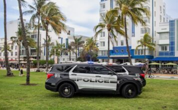 Florida Seizes Over $350K, 623 Slot Machines Amid Lawmakers’ Push for Anti-Gambling Bill Police SUVs parked on grass in front of palm trees and art deco buildings