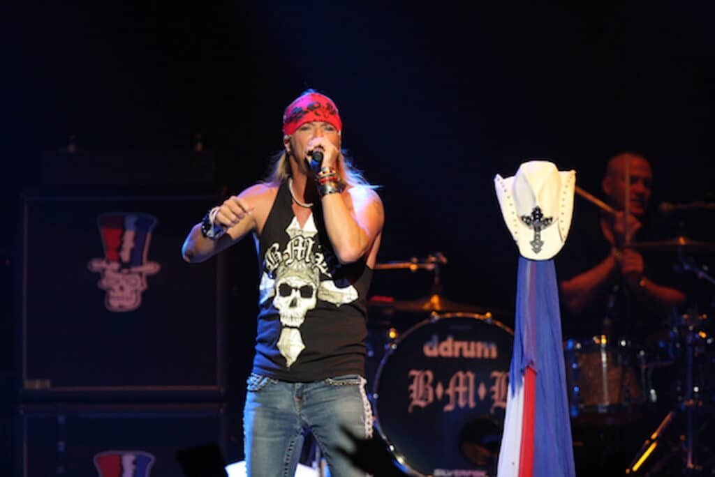 Bret Michaels performing live on stage with microphone and bandana
