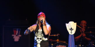 Bret Michaels performing live on stage with microphone and bandana