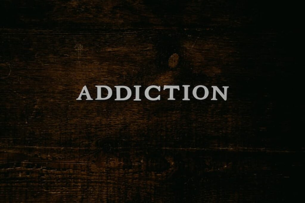 Word “Addiction” displayed on a dark wooden surface