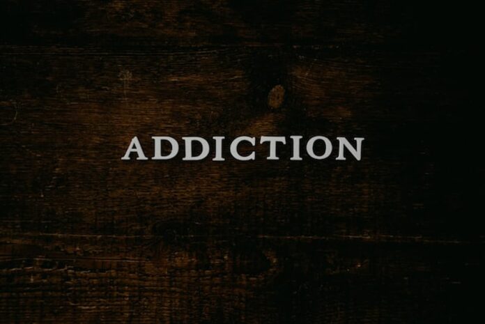 Word “Addiction” displayed on a dark wooden surface