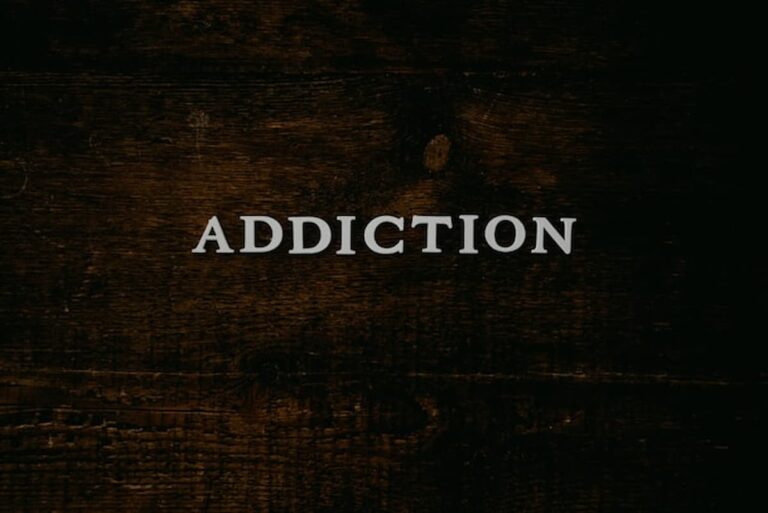 Word “Addiction” displayed on a dark wooden surface