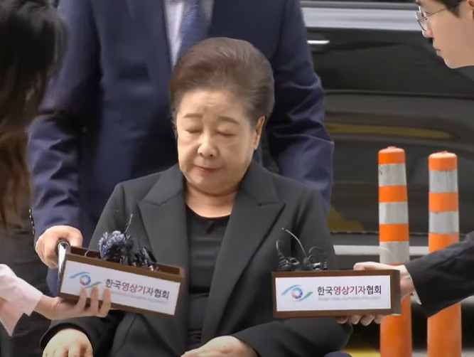 Reporters ask Unification Church leader Han Hak-ja questions as she arrives at a court in Seoul on September 23.