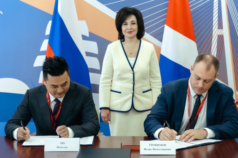 Liu Zhenhao (front left), the General Director of Jiangsu Xiuyuntong Investment, and Primorye Development Corporation chief Igor Trofimov (front right) sign a development agreement at the Eastern Economic Forum in front of Vera Shcherbina, the First Vice-Governor of Primorsky Krai.