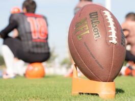 Close-up of an NFL football on a tee with blurred players in the background