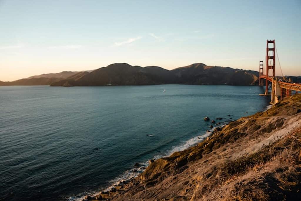 View of the Golden Gate Bridge and California coastline at sunset.