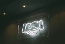 Underdog & Sportradar Announce Responsible Gaming Partnership Neon sign of a handshake