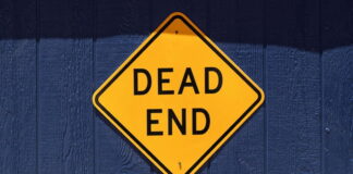 FAIR BET Act Blocked From Defense Bill, But Push to Restore Gambling Loss Deductions Continues Yellow diamond-shaped “Dead End” road sign mounted on a dark blue wooden wall.