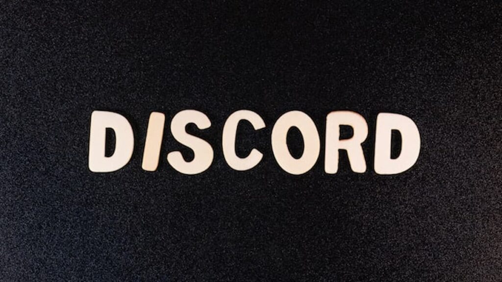 The word “DISCORD” spelled out in cutout letters on a black textured background.