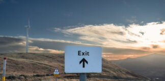Exit road sign pointing forward in open landscape