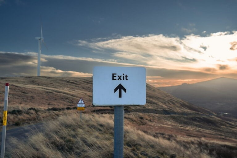 Exit road sign pointing forward in open landscape