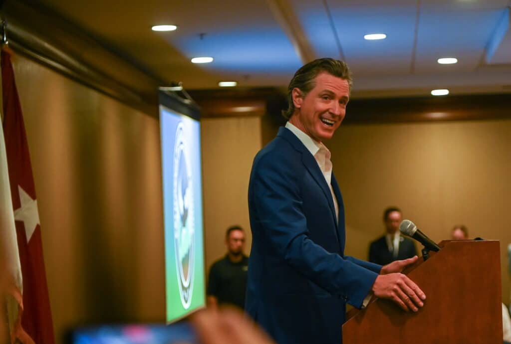Gavin Newsom speaking at a podium during the California Defense Leadership Summit in Sacramento