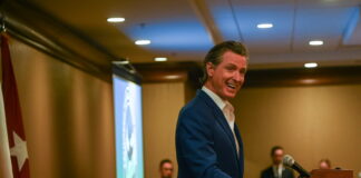 Gavin Newsom speaking at a podium during the California Defense Leadership Summit in Sacramento
