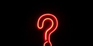 Bright red neon question mark glowing against a dark background
