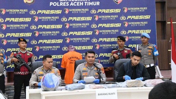 The East Aceh Police Chief Irwan Kurniadi (front, center) hosts a press conference with a man suspected of killing a delivery driver standing behind (rear, center).