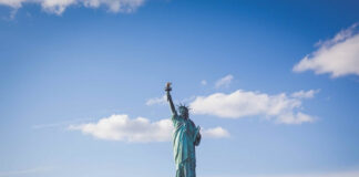 The Statue of Liberty against a bright blue sky with scattered clouds