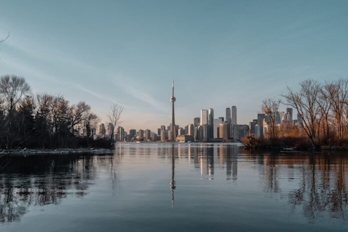 Toronto skyline with CN Tower viewed across the water at sunset.