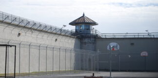 Former Washington State Employee Sentenced for Embezzling Nearly $900K to Fuel Gambling Habit Empty prison yard with barbed wire fences.