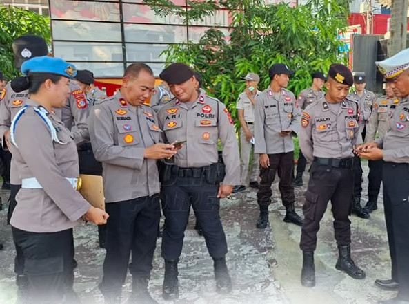 Senior officials check Poso police officers’ mobile phones for evidence of online gambling actively during an October 14 roll call.