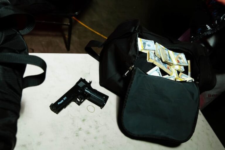 Handgun and duffel bag filled with stacks of cash on a table