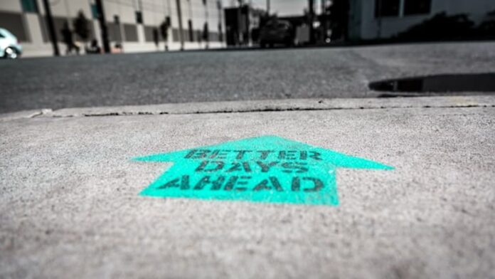 Arrow painted on pavement reading “Better Days Ahead.”