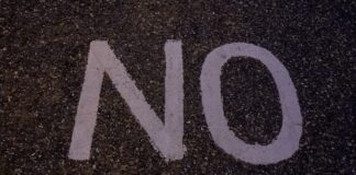 White “NO” painted on asphalt, symbolizing opposition or rejection